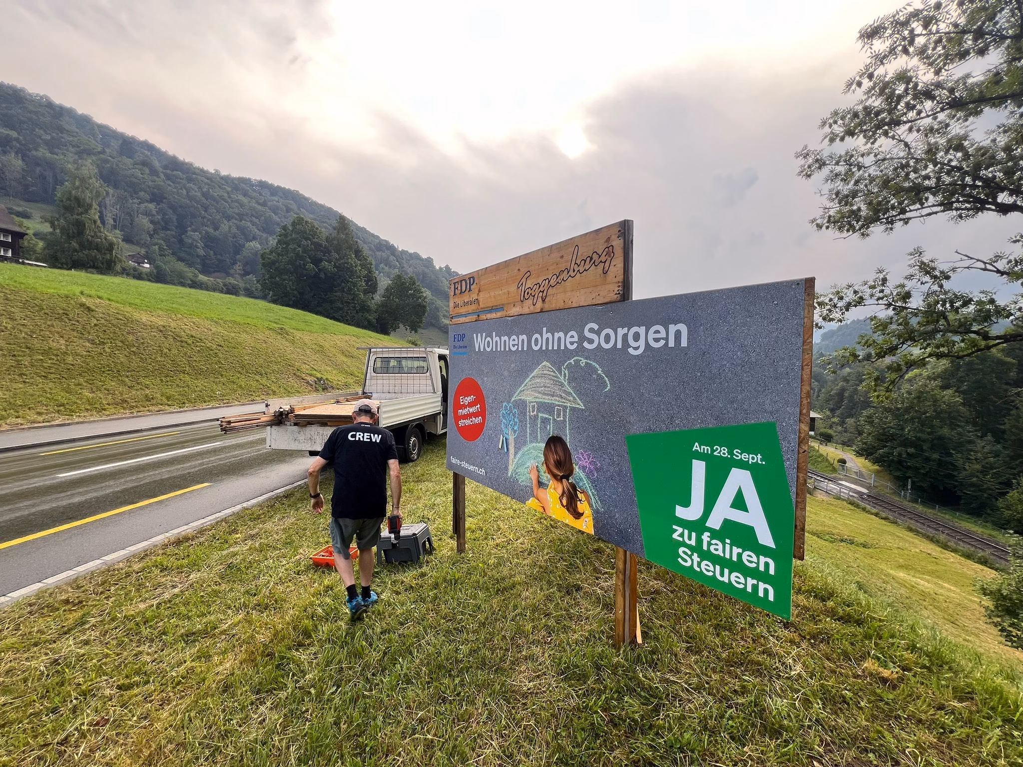 Aufstellen eines Plakats der Eigenmietwert-Kampagne an einer Strasse